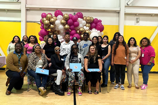 attendees pose at the entrance to the 2023 Women’s Empowerment Summit hosted by the YO! Watts YouthSource Center