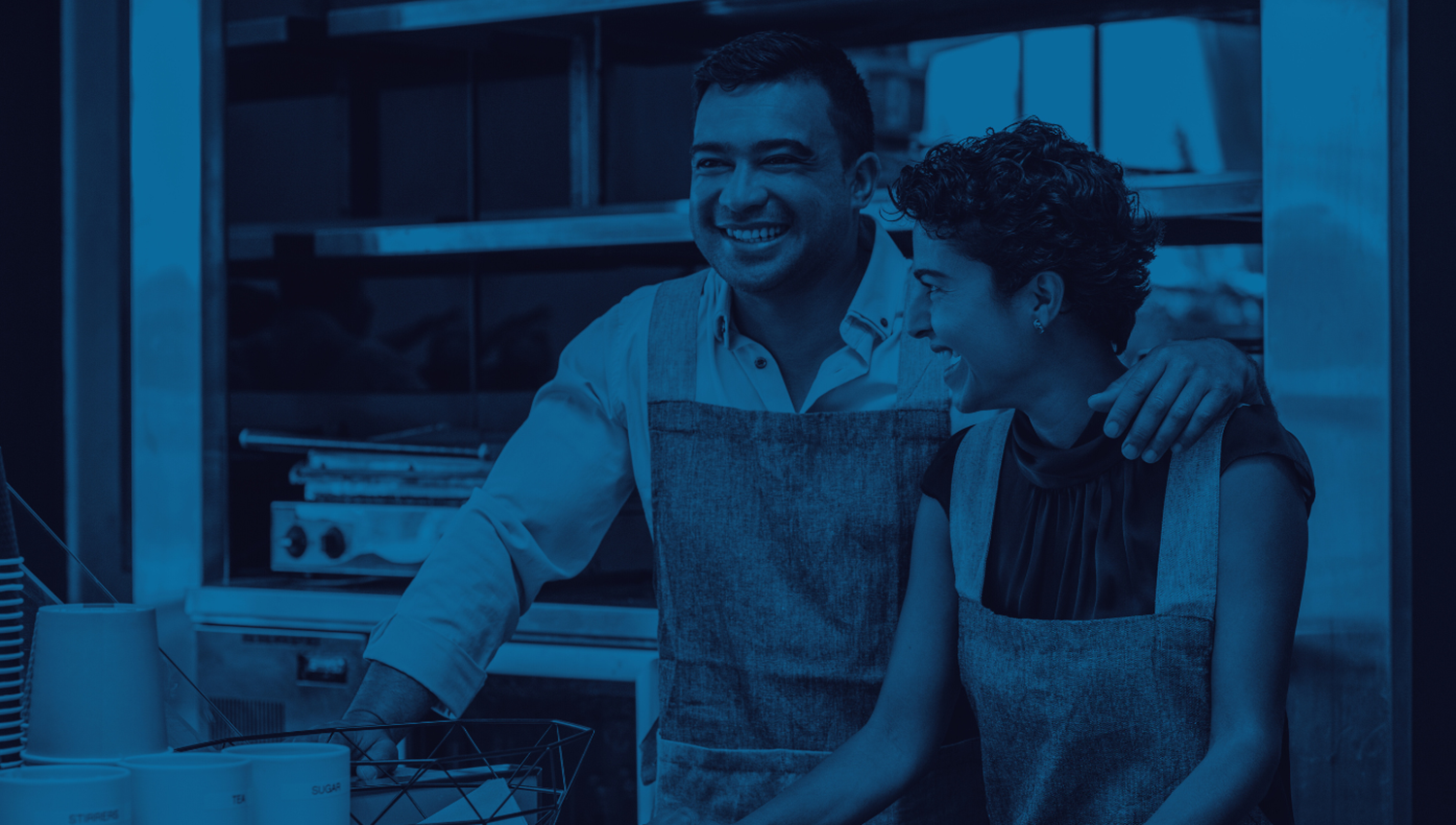small business owner with his son at the counter of a cafe, smiling and assisting customers